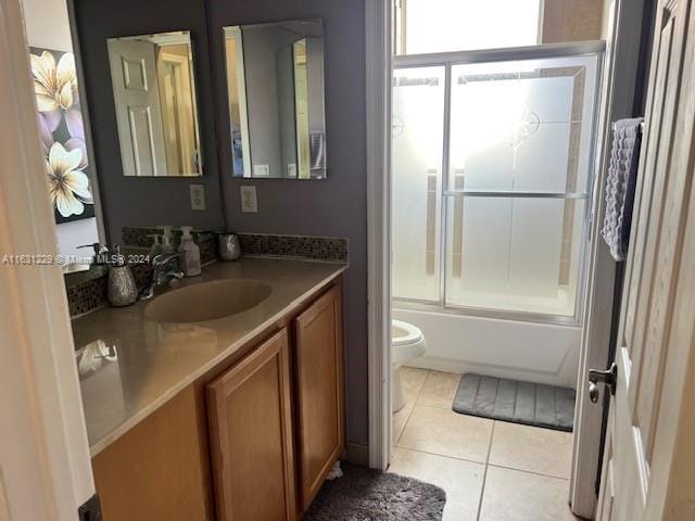 full bathroom featuring vanity, tile patterned floors, shower / bath combination with glass door, and toilet