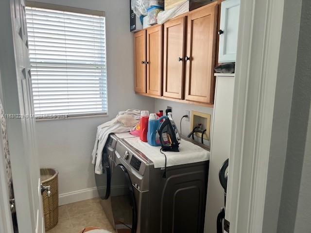 laundry room featuring cabinets, washing machine and dryer, and light tile patterned floors