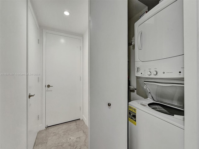 laundry room featuring light tile patterned flooring and stacked washer / drying machine