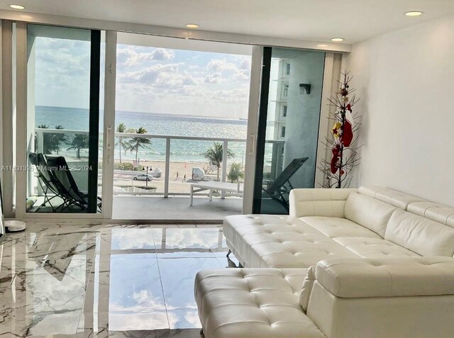 living room with a wall of windows, a water view, and a wealth of natural light