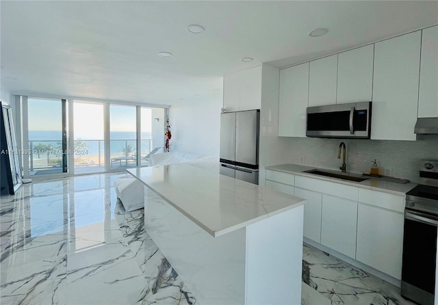 kitchen with white cabinetry, a kitchen island, appliances with stainless steel finishes, and sink