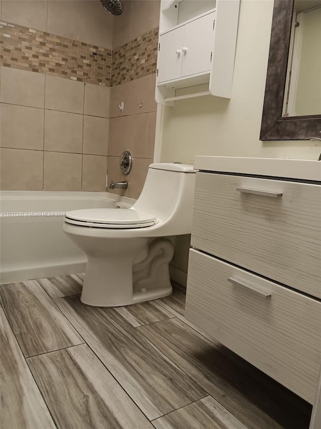 full bathroom featuring vanity, tiled shower / bath combo, and toilet