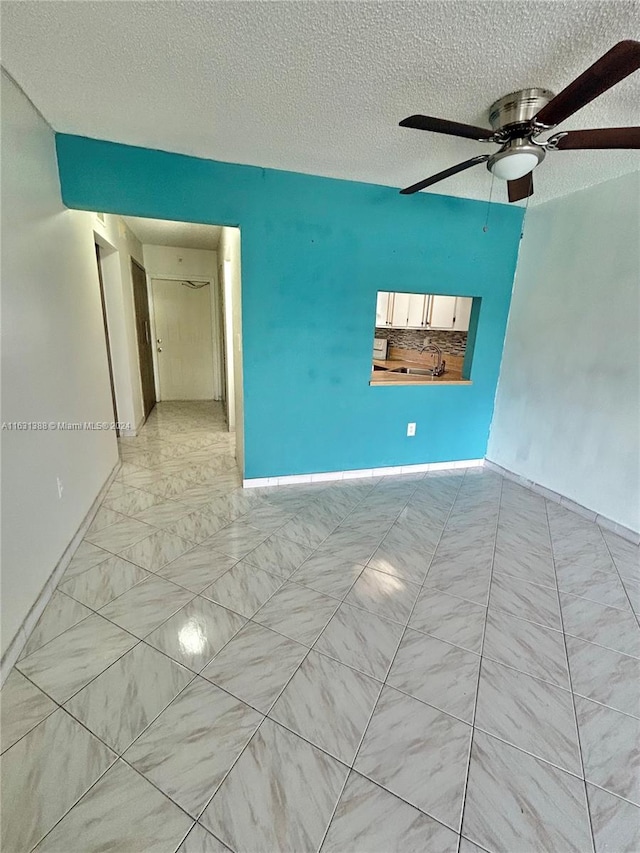 empty room with a textured ceiling and ceiling fan