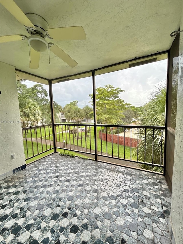 unfurnished sunroom with ceiling fan and a wealth of natural light