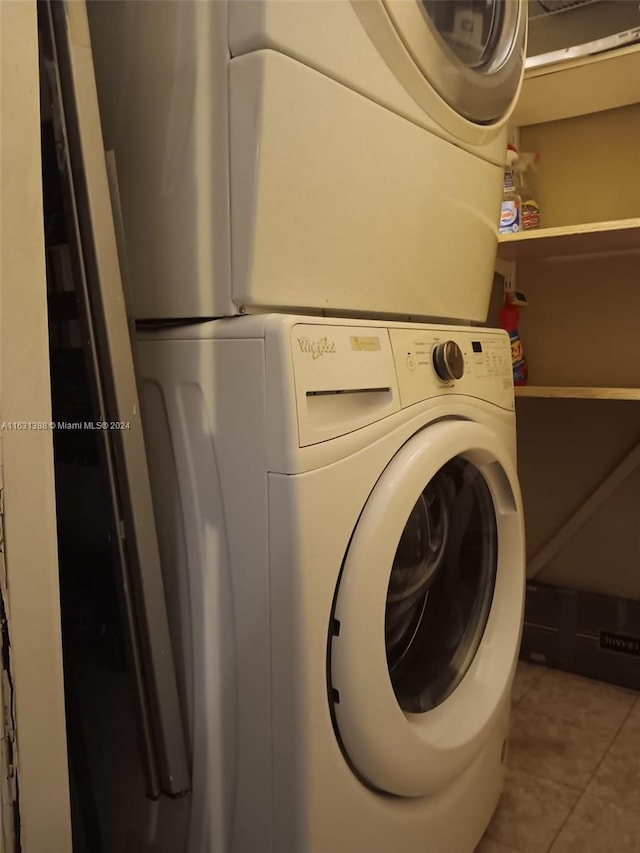 clothes washing area featuring stacked washer and dryer and tile patterned flooring