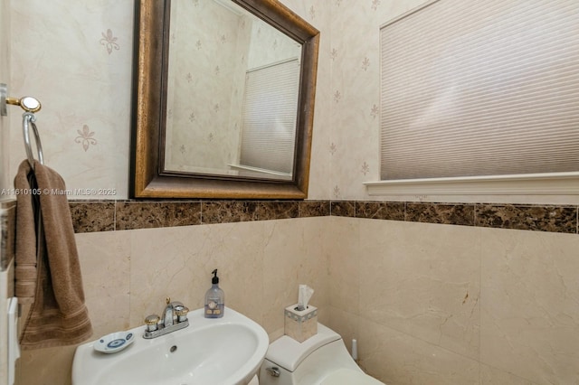 bathroom with sink, tile walls, and toilet