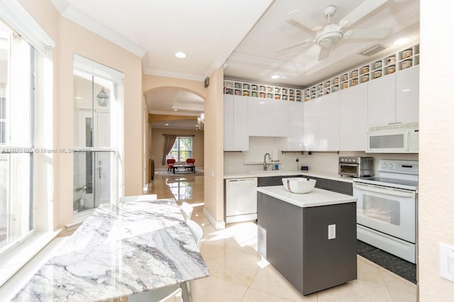 kitchen with sink, white appliances, white cabinets, and a kitchen island