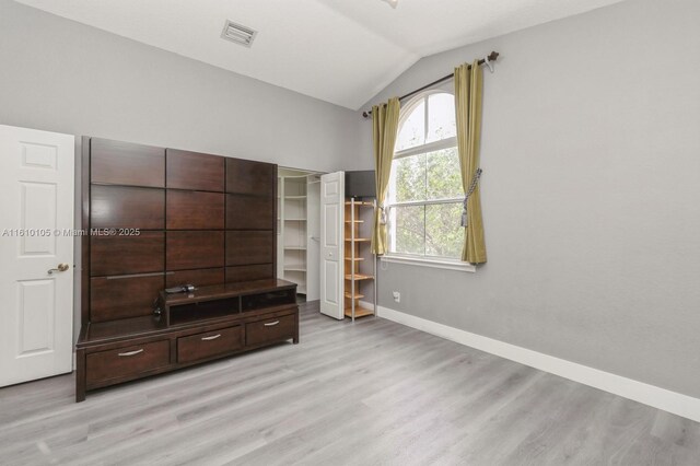 unfurnished bedroom featuring vaulted ceiling and light hardwood / wood-style floors