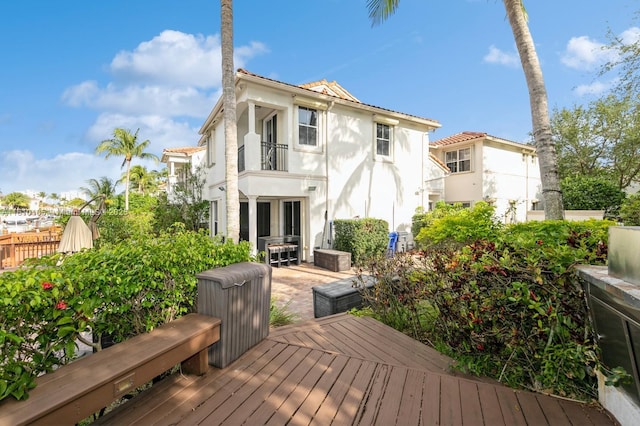 rear view of house featuring french doors, a balcony, a deck, and a patio area