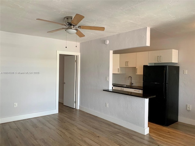 kitchen with hardwood / wood-style floors, backsplash, black fridge, sink, and ceiling fan