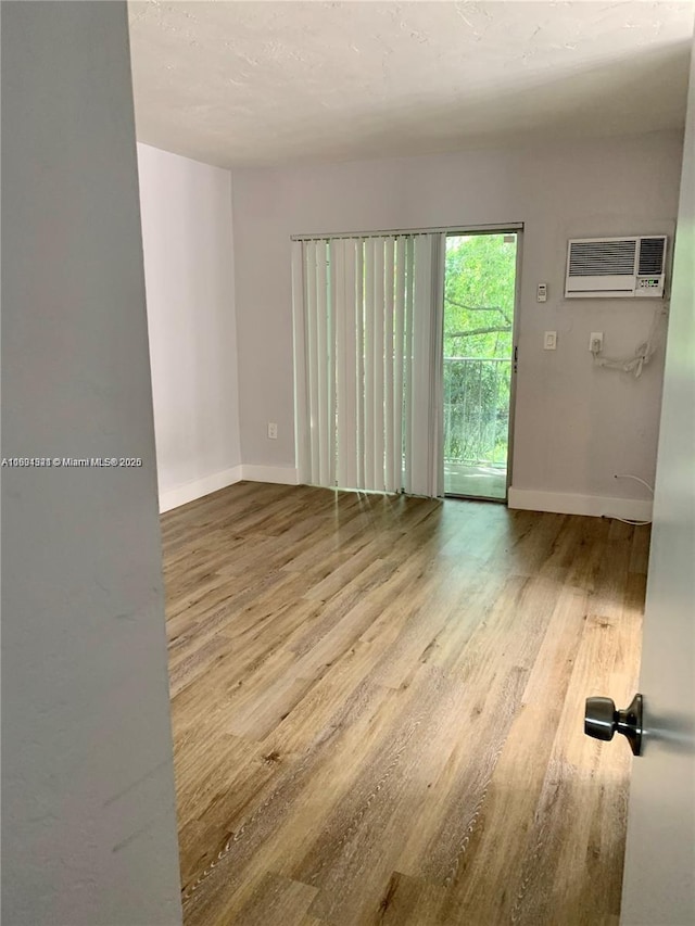 unfurnished room featuring light hardwood / wood-style flooring and an AC wall unit