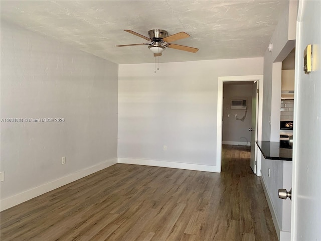 empty room with a fireplace, ceiling fan, a wall mounted air conditioner, and dark hardwood / wood-style floors