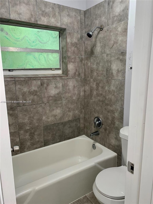 bathroom with tile patterned floors, toilet, and tiled shower / bath