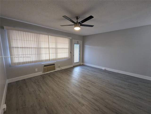 empty room with a wall unit AC, wood-type flooring, ceiling fan, and a textured ceiling