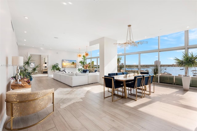 dining room featuring an inviting chandelier, a wall of windows, and light hardwood / wood-style floors