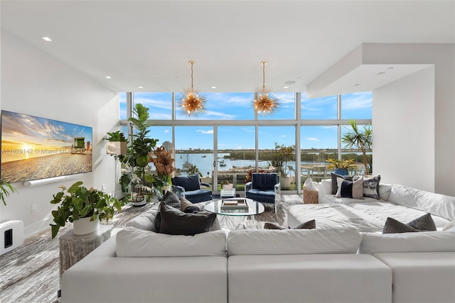 living room featuring a water view, plenty of natural light, expansive windows, and a notable chandelier