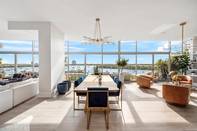 dining room with a water view, a wall of windows, light wood-type flooring, and a notable chandelier