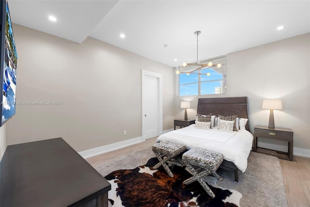 bedroom with a notable chandelier and light wood-type flooring