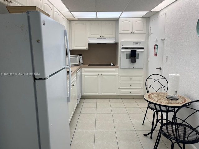 kitchen featuring light tile patterned flooring, white cabinetry, white appliances, and a drop ceiling