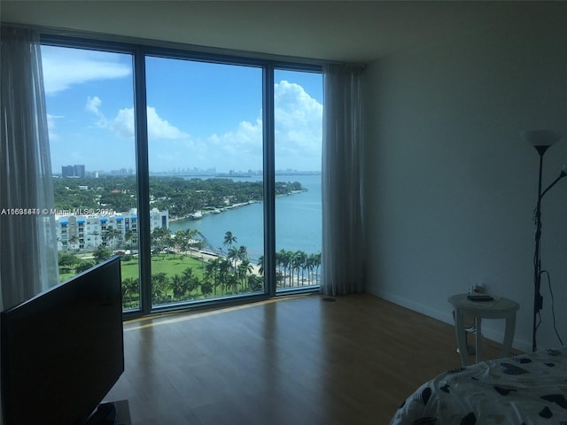 unfurnished bedroom with multiple windows, expansive windows, and hardwood / wood-style floors