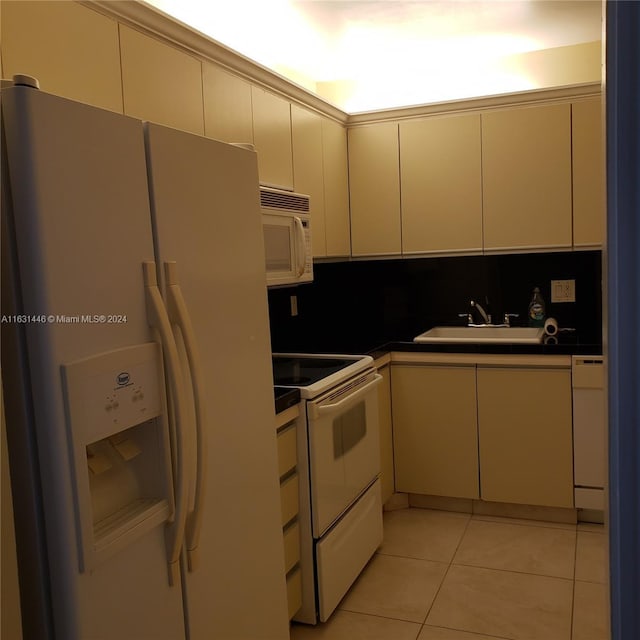 kitchen with dark countertops, white appliances, light tile patterned floors, and a sink