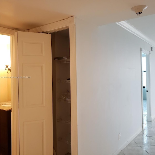 hallway featuring ornamental molding, light tile patterned flooring, and baseboards