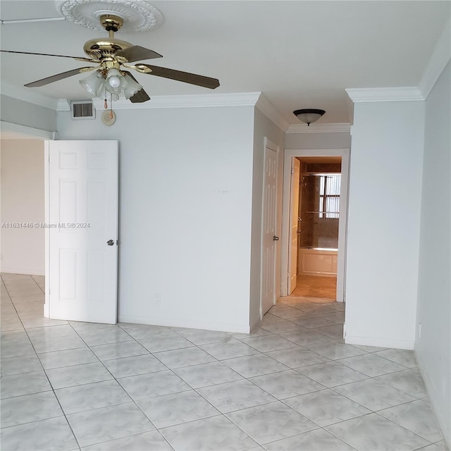 spare room featuring crown molding, light tile patterned floors, visible vents, a ceiling fan, and baseboards