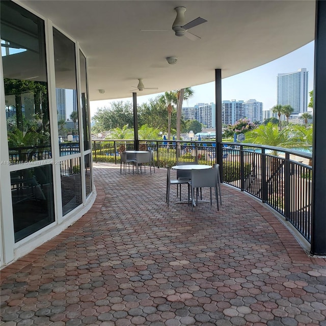 view of patio / terrace featuring a view of city, outdoor dining space, and a ceiling fan