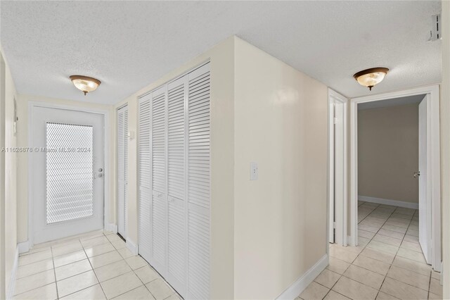 corridor featuring light tile patterned flooring and a textured ceiling