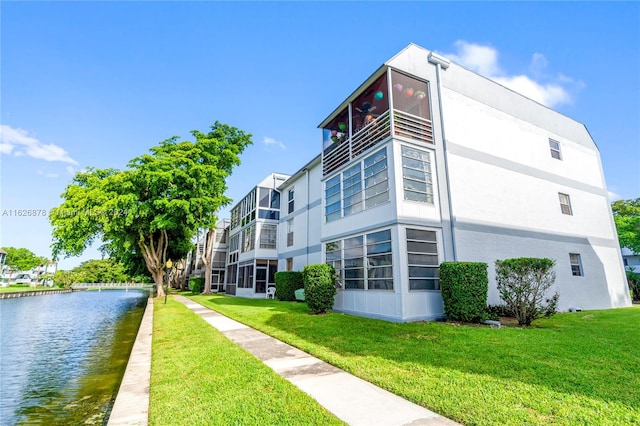 view of property exterior featuring a water view, a lawn, and stucco siding