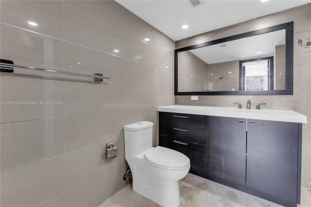 bathroom featuring vanity, tile walls, and toilet