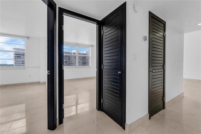 hall with floor to ceiling windows, plenty of natural light, and light tile patterned floors