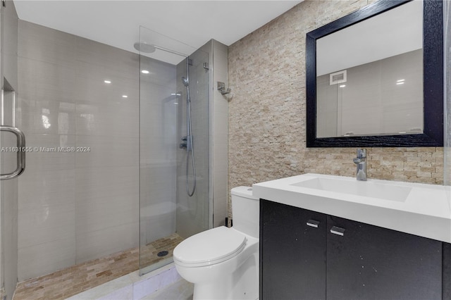 bathroom with vanity, tile walls, a shower with shower door, and toilet