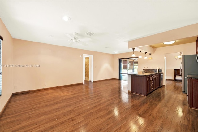 kitchen featuring dark stone counters, ceiling fan, hardwood / wood-style flooring, stainless steel fridge, and sink