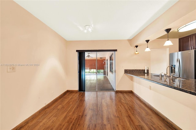 kitchen featuring stainless steel fridge, sink, decorative light fixtures, and dark wood-type flooring