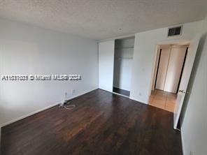 empty room with dark hardwood / wood-style floors and a textured ceiling