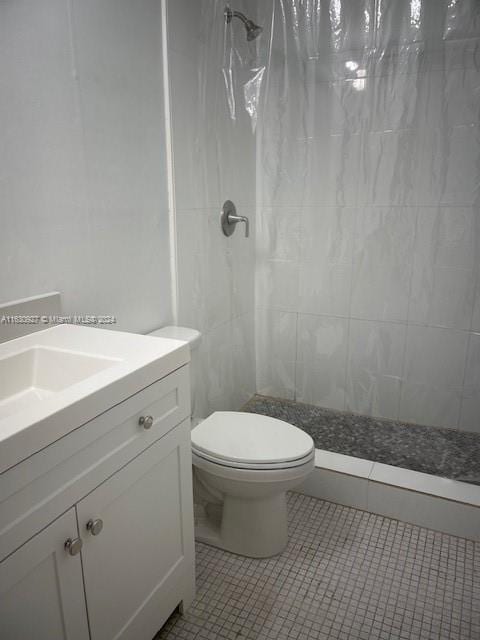 bathroom with toilet, vanity, tile patterned floors, and walk in shower