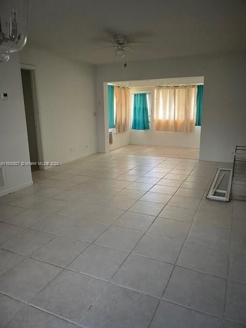 tiled empty room featuring ceiling fan