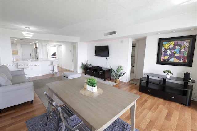 dining area with sink, wood-type flooring, and a textured ceiling