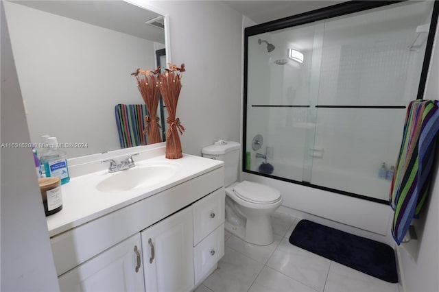 full bathroom featuring shower / bath combination with glass door, vanity, tile patterned flooring, and toilet