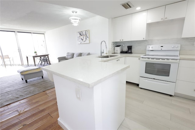 kitchen featuring pendant lighting, white electric range, sink, light wood-type flooring, and kitchen peninsula