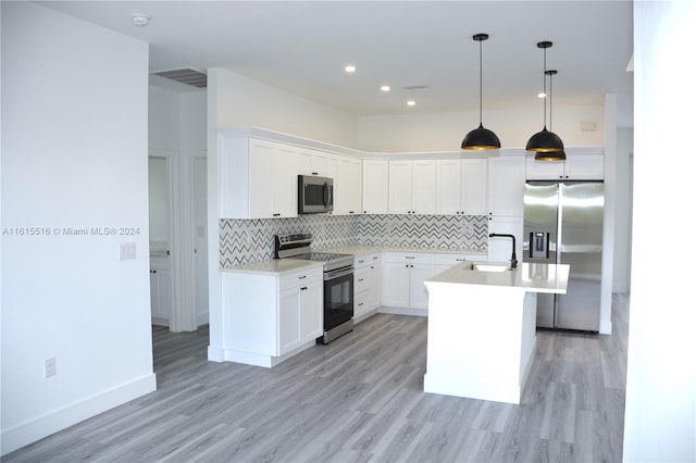 kitchen featuring light wood-type flooring, backsplash, stainless steel appliances, sink, and a center island with sink