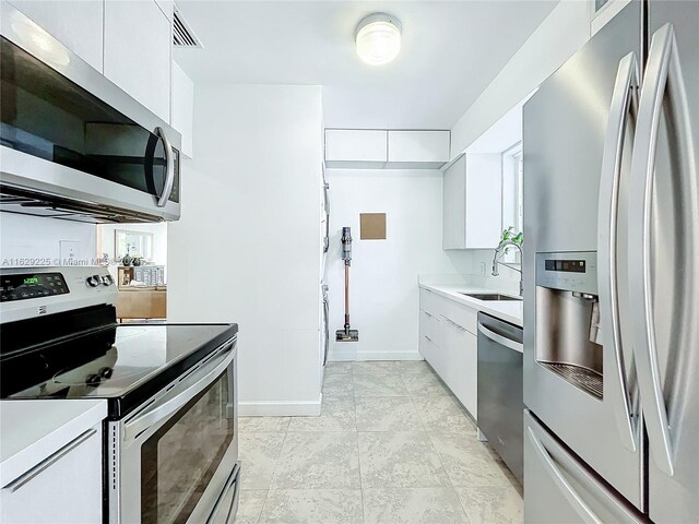 kitchen with sink, white cabinetry, stainless steel appliances, and light tile patterned floors