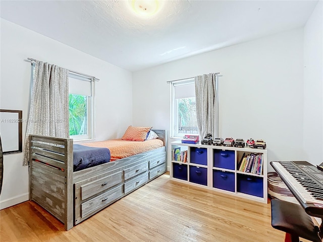 bedroom with multiple windows and light wood-type flooring