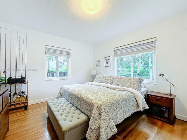 bedroom with multiple windows and hardwood / wood-style flooring