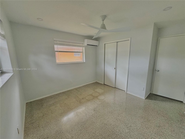 unfurnished bedroom with a closet, a textured ceiling, a wall unit AC, and ceiling fan