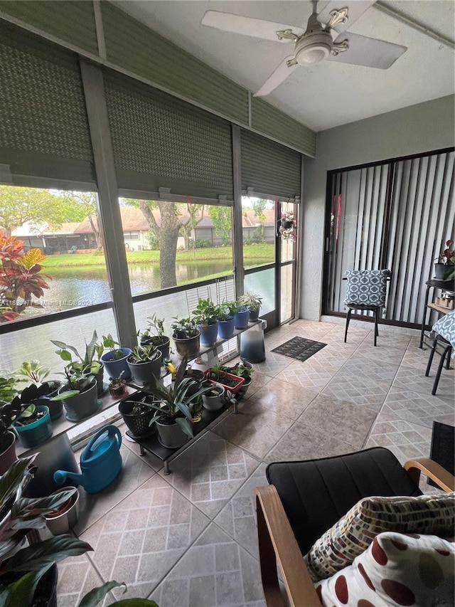 sunroom featuring a water view and ceiling fan