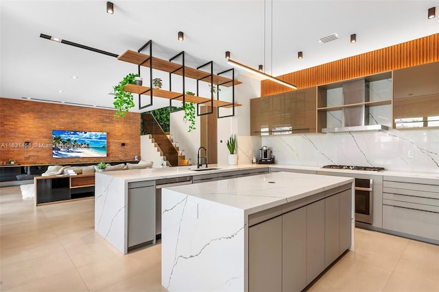 kitchen with gray cabinets, sink, a center island, and wall chimney range hood