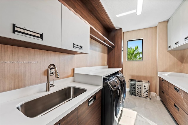 clothes washing area featuring light tile patterned floors, washer and dryer, sink, and cabinets