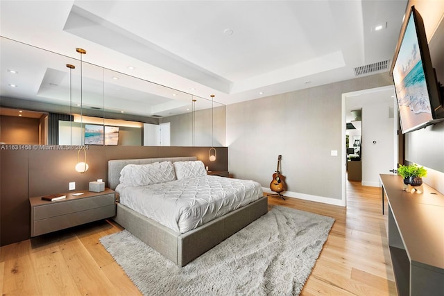 bedroom featuring a tray ceiling and light hardwood / wood-style floors